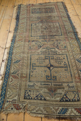 Antique Caucasian runner's tattered end, showing wear and loss on beige field, geometric border.