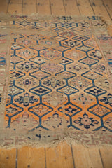 Worn tangerine and inky blue lattice-medallion pattern on this antique Caucasian fragment rug.