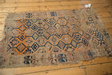 Bottom corner of antique Caucasian rug, tattered fringe, geometric border, orange medallions.