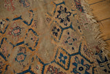Geometric multi-medallion pattern with threadbare texture and visible tatter on antique Caucasian rug.