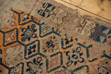 Visible threadbare antique Caucasian rug featuring allover multi-medallion pattern in tangerine, inky blue, beige.