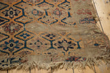 Antique Caucasian rug fragment, threadbare geometric medallions, faded blue, orange, and tattered fringe.
