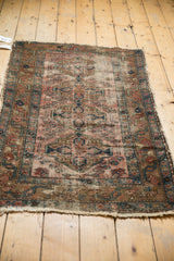 Detail of antique Lilihan rug end, showcasing faded brick red vinery and secure, tattered edge.
