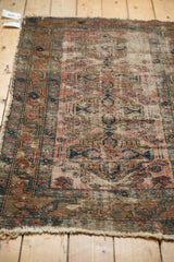Antique Lilihan rug's tattered side and worn fringe, showing faded brick red and blue patterns.