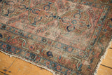 Worn side and faded geometric border of an antique Lilihan rug in brick red and blue.