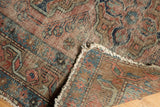 Antique Lilihan rug corner showing faded brick red, blue vinery, overcast securing, and textured foundation.