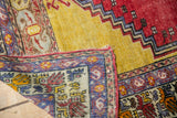 Corner of vintage Melas rug showing hand-knotted foundation, overcast end, and multi-color patterns.