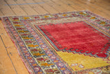 Vintage Melas rug showing cherry red field, saffron Ladik panel, and colorful boteh border.