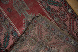 Folded corner of an antique Karabagh rug revealing the hand-knotted foundation and restored fringe.