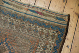 Antique Belouch rug corner showcasing indigo blue geometric border, madder red motifs, and dark selvage.
