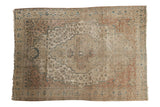 Antique Farahan Sarouk rug, elongated central medallion, intricate floral vinery in sand, faded brick red, and dusty blue.