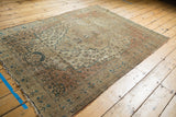 Tattered end and side of Antique Farahan Sarouk rug showing faded brick red and blue motifs.