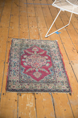 High-angle perspective of the antique Kerman rug's fuchsia and blue floral pattern.