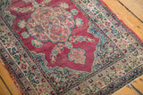 Angled view of a fuchsia Kerman rug's time-softened pile and detailed floral borders.