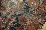 Worn pile and tattered border of an antique Malayer rug, featuring aged blue and red patterns.