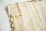 Detail of folded antique Casco Bay map, showing wear, tape, and rustic weights.