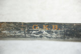 Orange stenciled initials G.K.B. on a weathered and distressed black metal map tube.