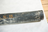 Orange stenciled initials K.B. on the heavily worn dark metal surface of a ship map tube.