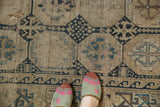 Visible tatter and primitive geometric motifs on antique Caucasian rug in navy and ivory.
