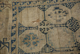 Geometric navy and ivory patterns on an antique Caucasian rug, with visible foundation.