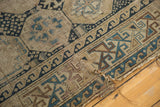 Primitively drawn geometric motifs in brown, blue, and ivory on an antique Caucasian rug fragment with wear.