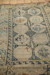 Antique Caucasian rug fragment showing worn navy, sky blue, and pale bronze geometric motifs.