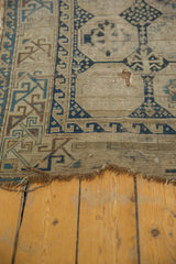 Tattered bottom edge of antique Caucasian fragment rug with geometric navy and beige designs.