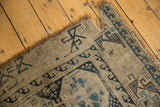 Geometric navy blue and pale bronze motifs on a worn antique Caucasian fragment edge.