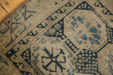 Worn pile of antique Caucasian rug showing geometric motifs in navy, sky blue, and beige.