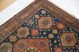 Close-up of a slightly tattered corner on a fine antique Tehran rug, showing the low pile and geometric borders.
