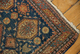 A worn, tattered corner of an antique Tehran rug with a complex geometric border.