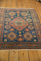 Antique Tehran rug shown from an angle, featuring its Caucasian-style geometric motifs and central medallion.