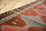 Antique Bakshaish runner's geometric border and diamond medallion on an abrashed pomegranate field.