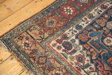 Intricate geometric borders in navy, sky blue, and russet on an antique Bijar rug corner.