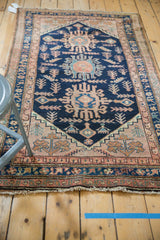 Vintage Hamadan rug lower left corner, with navy blue and pale blush borders framing geometric plant motifs.