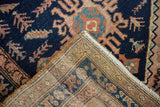 Folded corner of vintage Hamadan rug, revealing navy field pile and intricate hand-knotted foundation.