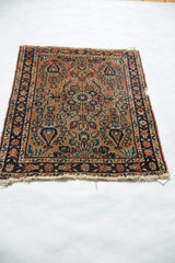 Vintage Lilihan rug mat corner with tattered fringe, dusty rose field, and navy floral border.