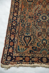 Tattered fringe and corner of the vintage Lilihan rug with dusty rose field and navy border.
