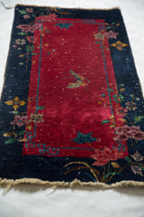 Art Deco Chinese rug texture: wine red field, navy border, visible white knots, tattered fringe.