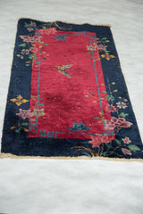 Vintage Art Deco Chinese rug corner with wine red field, blush floral sprays, and tattered fringe.