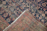 Antique Malayer rug folded corner showing hand-knotted reverse, foundation wear, and navy, red blush Herati pattern.