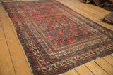 Angled view of antique Malayer rug, showing overall intricate design and aged madder red pile.