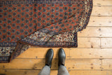 Intricate botehs on madder red vintage Malayer rug corner with navy border and light tatter.
