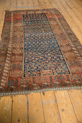 Antique Kurdish rug with intricate boteh pattern on cobalt blue field and faded red borders.