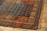 Antique Kurdish rug corner featuring woven fringe and intricate madder red geometric border.