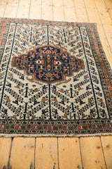 Vintage Afshar rug: ivory ground, navy, terracotta serrated medallion, allover bird motif.