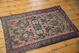 Antique Lilihan rug corner detail, revealing blush field with indigo and green floral motifs, and pile wear.