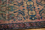 Detailed view of antique Lilihan rug's blush ground, Mahi figures, and indigo border with wear.