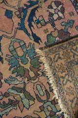Antique Persian Lilihan rug showing blush pile, blue floral motifs, and woven back with frayed fringe.