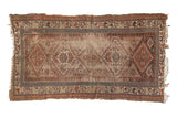 Aged antique Kurdish rug with geometric patterns, madder red, beige, and blue tones.